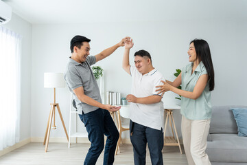 Asian attractive family dancing with young son in living room in house