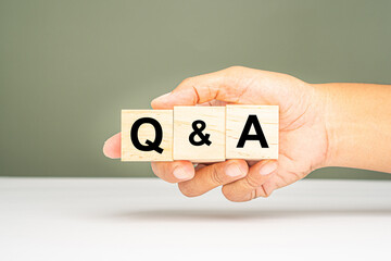 Question and Answer concept. Hand holding of wooden cubes with words Q and A