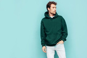 Handsome confident hipster  model. Sexy unshaven man dressed in summer stylish green hoodie and...
