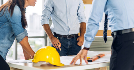 Professional of team architect industrial engineer cargo foreman in helmet working new construction project architectural plan with blueprint and construction tool at the building construction site