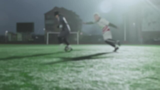 Soccer player makes dribble feint and run to goal. Blurred. Unexpected maneuver, deceptive movement. Football game in the evening in small stadium. Teams are playing amateur semi-professional match