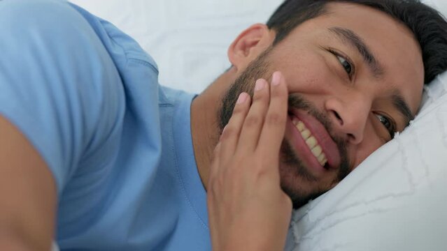 Face, love and bed with a hand touching a man in lying in a bedroom on a weekend morning. Couple, wake up and together with an asian male sharing an intimate moment with a wife or girlfriend at home