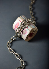 UAE Dirham notes wrapped with metal chain. Concept for stagnant economy' or 'economic crisis'.