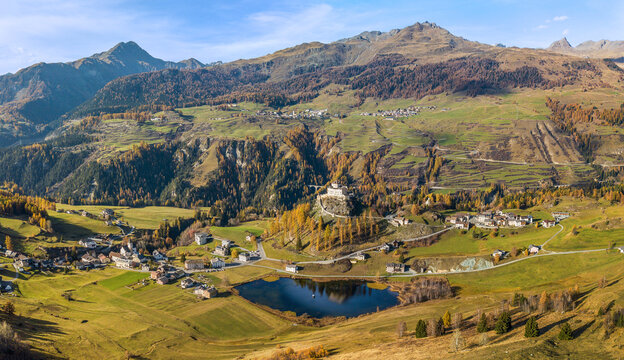 Tarasp, Switzerland - October 30. 2022: Aerial panorama of the Tarasp valley with an old castle in autumn color.