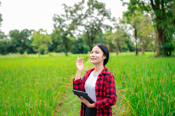 young asian agronomist farmer smiling and holding mobile smart tablet