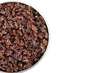 Dark-colored raisins lying in a metal container, shot on a white background.