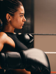 Sideview of a female boxer standing against the ropes in a boxing ring