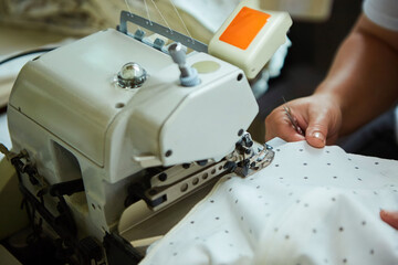 Industrial sewing production or atelier. The hands of tailors sewing fabrics on sewing machines to create clothes.