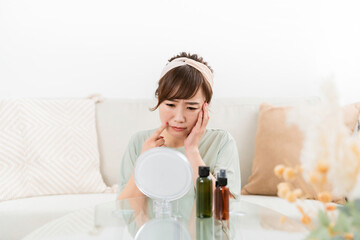 鏡を見て肌に悩む女性（ほうれい線・シワ）
