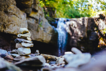 A pyramid of stones balances in nature against the backdrop of a waterfall. feng shui peace and quiet