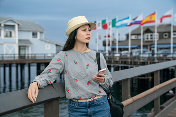 portrait of asian taiwanese female traveler resting arm on pier railing and gazing into distance...