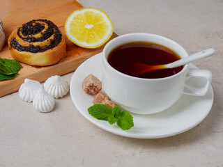 mint tea in a white cup with cookies and lemon on white marble, flat plate