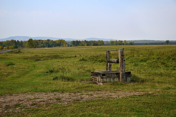 An old wooden abandoned well on the edge of the village. Autumn landscape.