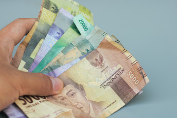 hand holding Indonesian state money, with gray copy space or negative space, Indonesian rupiah