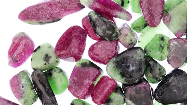Ruby zoisite jewel stones heap up texture on light white isolated background. Moving right seamless loop backdrop.