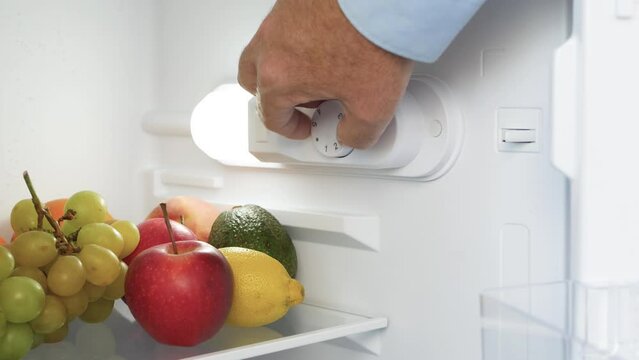 Man Hand Open the Kitchen Fridge Door and Set the Thermostat. Making the Fridge Temperature Control for Optimum Function.