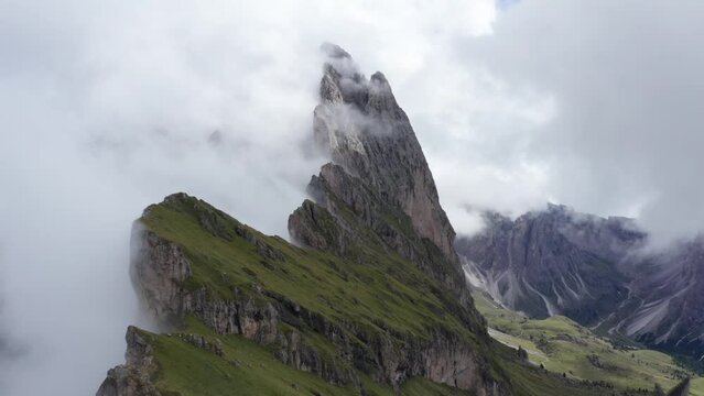 Drone flight over Seceda ridge with view of Fermeda Towers in clouds, Dolomites