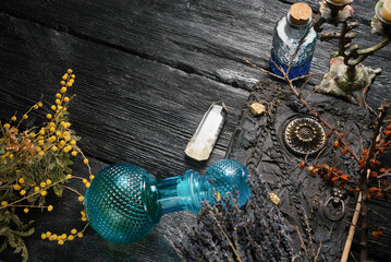 Old magic book and dry natural herbs and remedy bottle on the wooden table flat lay background with...