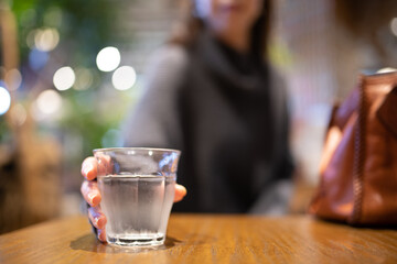 テーブル置かれた水を手に取る女性