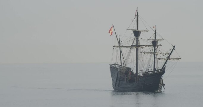 Ferdinand Magellan Nao Victoria carrack boat replica with spanish flag sails in the mediterranean at sunrise in calm sea in slow motion 60fps