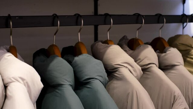 Winter down jackets hanging on hangers in the store close-up, side view.