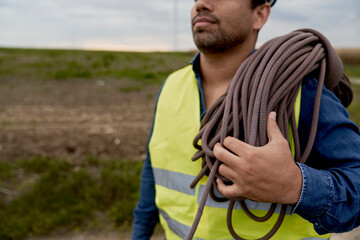 Close up of latin male maintenance engineer carrying climbing rope