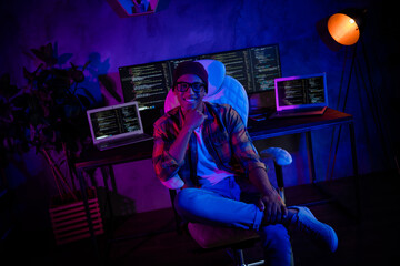 Photo of positive intelligent hacker sitting chair hand touch chin server operating evening loft...