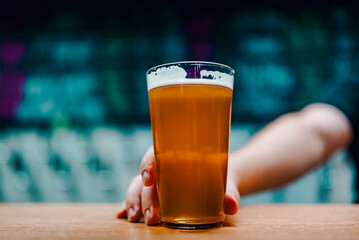 bartender's hand hold full glass of craft beer in a bar or taproom