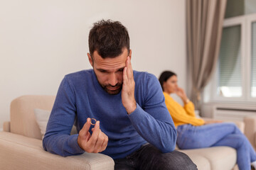 Stressed man holding her wedding ring worried about breakup or divorce, avoid talking with wife after fight, anxious couple ignore each other. Frustrated sad husband taking off the wedding ring