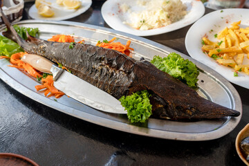 Hot smoked whole sturgeon on the dish with knife
