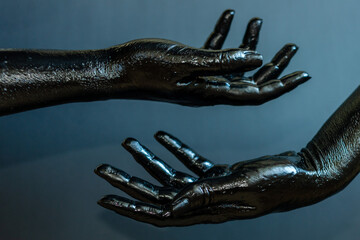 Elegant woman's hands with black paint on her skin with black background