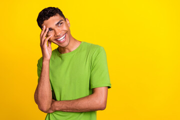 Photo portrait of handsome young man hand touch head smile look empty space wear stylish green clothes isolated on yellow color background