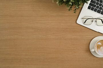 Simple workplace with laptop computer, eyeglasses and coffee cup on wooden table
