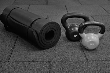 sports weights, rubber mat for fitness on the rubber floor in the gym, black and white photography. Bodybuilding equipment. Fitness or bodybuilding concept background.