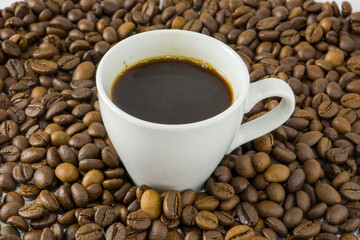 Coffee beans on a black background with a white cup.