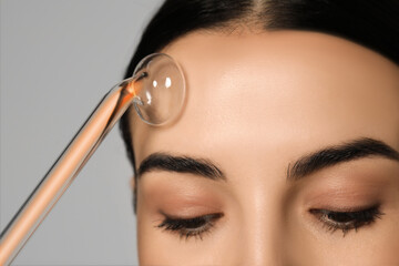 Woman using high frequency darsonval device on grey background, closeup