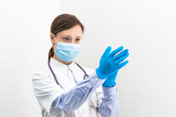 Beautiful young doctor woman in a medical mask and gloves with a stethoscope in a hospital during the coronavirus pandemic. Selective focus. Portrait. Close-up