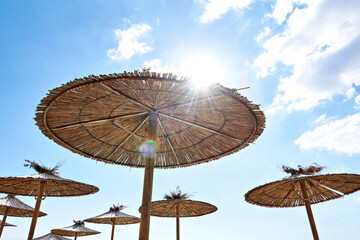 Beach wooden umbrellas on sand by sea