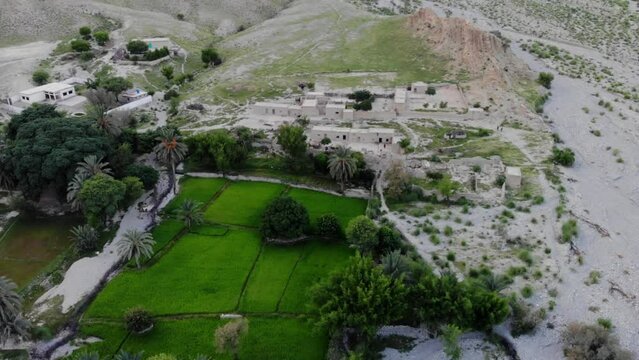 Aerial shot of green patch of land and mud houses in arid area of Khuzdar Balochistan.