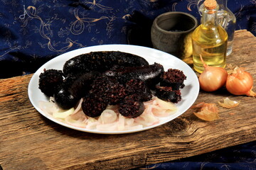 Baked black pudding with pickled onions on a white plate. Sliced and fried blood sausage on a plate