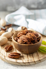 Fototapeta na wymiar Nuts and seeds, healthy fats, various trace elements and vitamins. Bowl with pecan nuts on a stone table. Copy space.