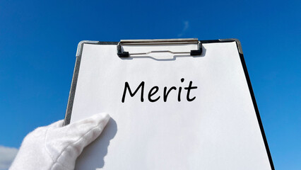 Meritの文字入りクリップボードを持つ白手袋の手_青空背景