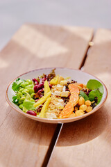Salad with pumpkin, mango, beans,  lettuce and tofu on a wooden table. Healthy vegetarian food.