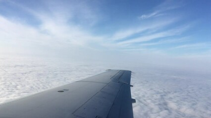 View from aircraft window of wing and clouds. 
