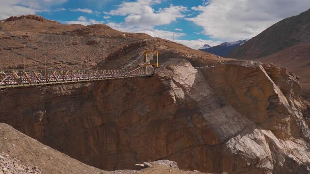 Chicham bridge in background of mountains during sunny day in Kibber, Spiti Valley, India. Connects the two villages Chicham and Kibber. Highest suspension bridge of Asia. 4,145 meters above sea level