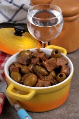 Cocotte de veau aux olives et un verre d'eau en gros plan