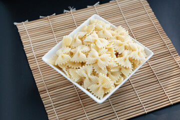 Farfalle pasta in a bowl. Cooked bow tie shape macaroni in white bowl.
