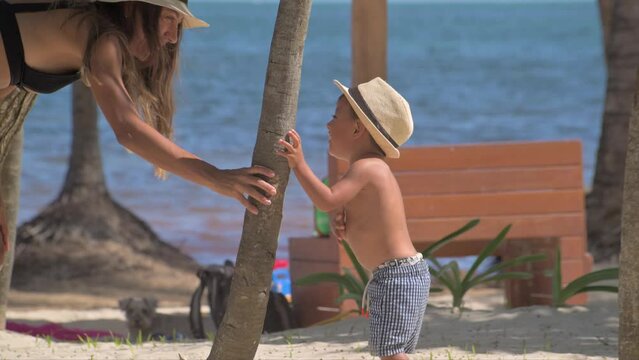 Young latin baby boy playing hide and seek with his mom at the beach laughing and having a great time on a sunny hot day. Slow motion