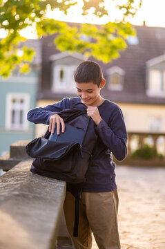 Smiling dark-haired adolescent rummaging in his schoolbag