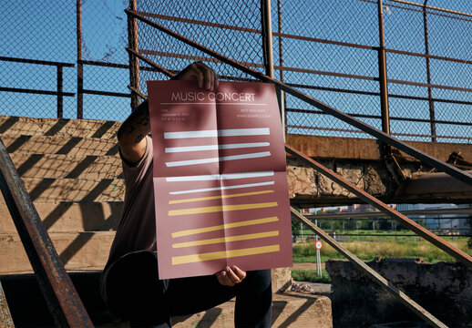 Man Holding a Vertical A2 Potser Mockup sitting on Stairs